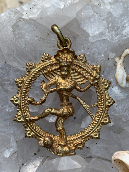 Pendentif en 'laiton argenté ou doré' de la divinité hindoue 'Shiva' sous sa forme de Shiva Nataraj. * Le roi (raja) de la danse (nata) est un symbole du mouvement éternel de l'univers, la danse cosmique. 4,5 cm de diamètre, vendu avec cordon !