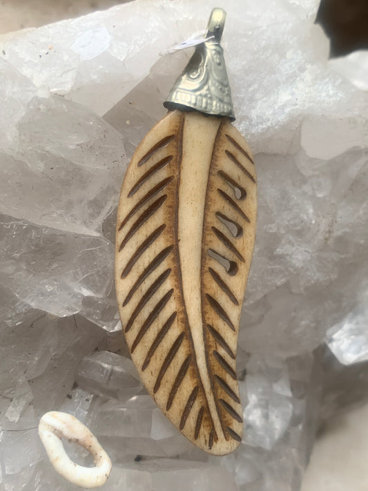 Pendentif artisanal du Népal en forme de plume, sculpté dans de l’os, de 70 millimètres de hauteur x 22 de largeur x 5 d'épaisseur. Vendu avec cordon noir réglable offert, parfait !