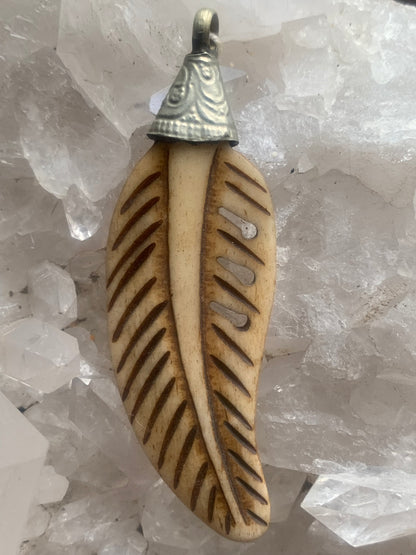 Pendentif artisanal du Népal en forme de plume, sculpté dans de l’os, de 70 millimètres de hauteur x 22 de largeur x 5 d'épaisseur. Vendu avec cordon noir réglable offert, parfait !