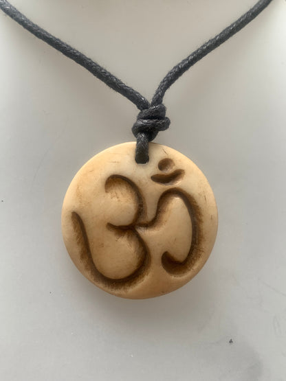 Pendentif artisanal du Népal avec symbole Om, sculpté dans de l’os, de 30 millimètres de diamètre x 4 mm d'épaisseur. Vendu avec cordon noir réglable offert, parfait !