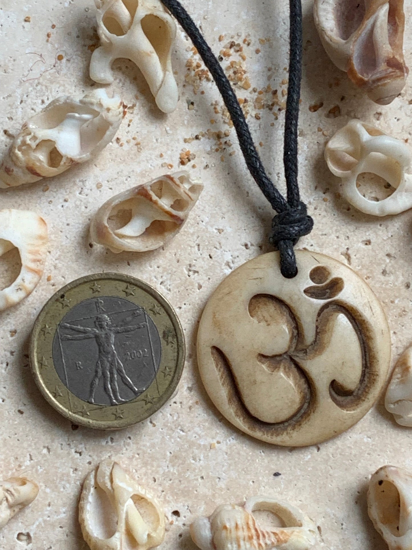 Pendentif artisanal du Népal avec symbole Om, sculpté dans de l’os, de 30 millimètres de diamètre x 4 mm d'épaisseur. Vendu avec cordon noir réglable offert, parfait !