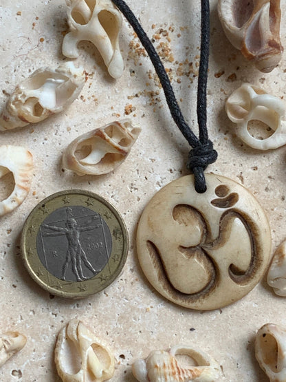 Pendentif artisanal du Népal avec symbole Om, sculpté dans de l’os, de 30 millimètres de diamètre x 4 mm d'épaisseur. Vendu avec cordon noir réglable offert, parfait !