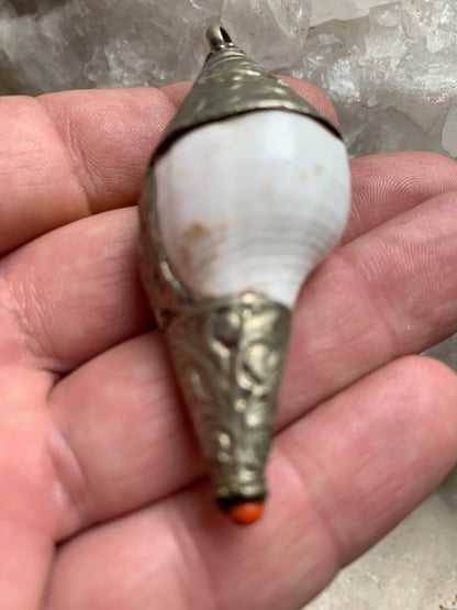 Pendentif artisanal du Népal en coquillage sertis en métal avec de jolies gravures et une perle de corail ! De 65 millimètres de hauteur x 28 mm de diamètre. Vendu avec cordon noir réglable offert, parfait !
