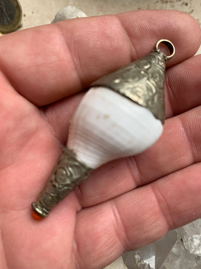 Pendentif artisanal du Népal en coquillage sertis en métal avec de jolies gravures et une perle de corail ! De 65 millimètres de hauteur x 28 mm de diamètre. Vendu avec cordon noir réglable offert, parfait !