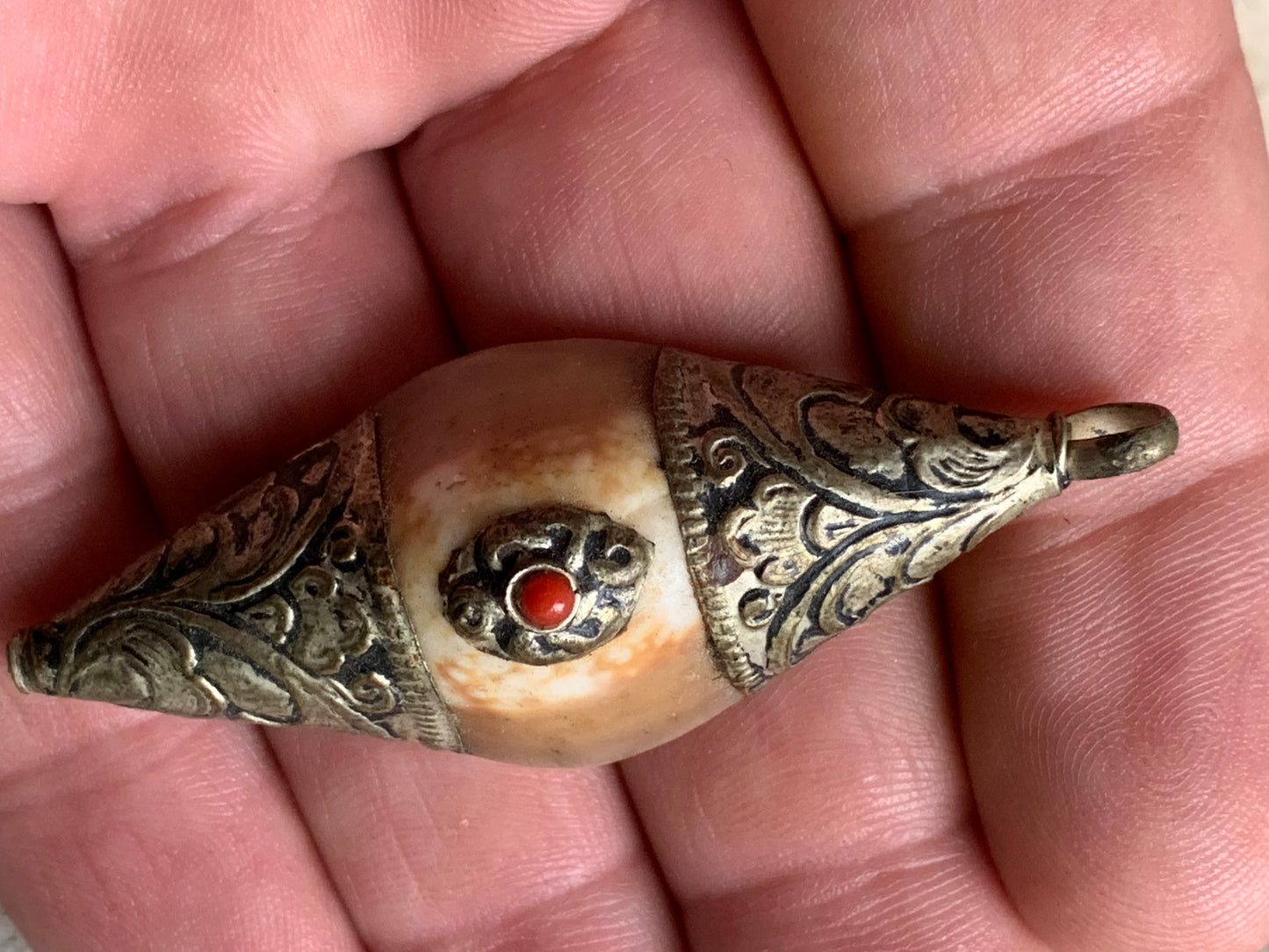 Pendentif artisanal du Népal en coquillage sertis en métal avec de jolies gravures et une perle de corail ! De 60 millimètres de hauteur x 23 mm de largeur x 16 d'épaisseur. Vendu avec cordon noir réglable offert, parfait !