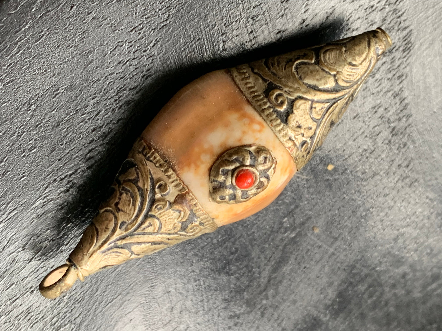 Pendentif artisanal du Népal en coquillage sertis en métal avec de jolies gravures et une perle de corail ! De 60 millimètres de hauteur x 23 mm de largeur x 16 d'épaisseur. Vendu avec cordon noir réglable offert, parfait !