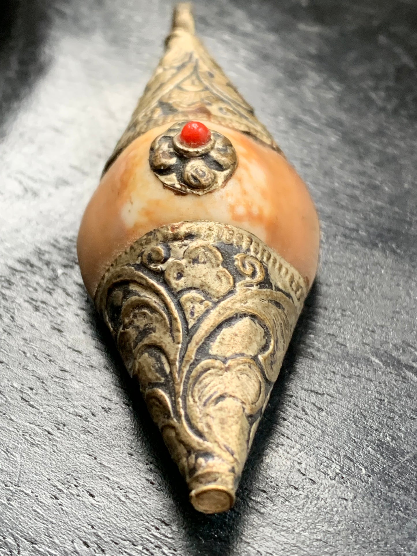Pendentif artisanal du Népal en coquillage sertis en métal avec de jolies gravures et une perle de corail ! De 60 millimètres de hauteur x 23 mm de largeur x 16 d'épaisseur. Vendu avec cordon noir réglable offert, parfait !