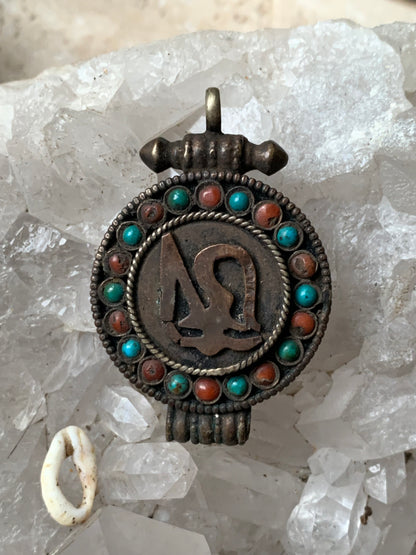 Pendentif/ Reliquaire artisanal du Népal avec pierres de turquoise et de corail sertis sur métal avec jolie gravure du Om ! De 52 millimètres de hauteur x 35 mm de largeur x 11 d'épaisseur. Vendu avec cordon noir réglable offert, parfait !