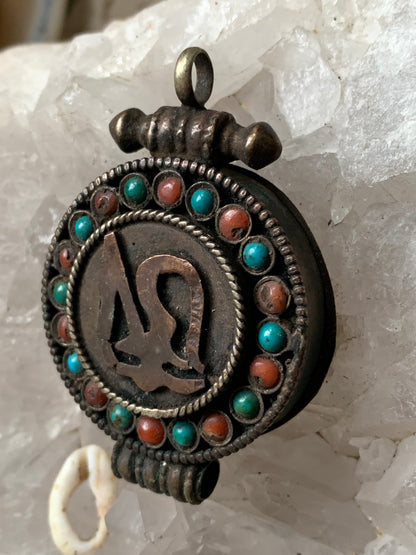 Pendentif/ Reliquaire artisanal du Népal avec pierres de turquoise et de corail sertis sur métal avec jolie gravure du Om ! De 52 millimètres de hauteur x 35 mm de largeur x 11 d'épaisseur. Vendu avec cordon noir réglable offert, parfait !