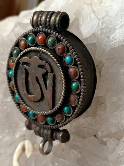 Pendentif/ Reliquaire artisanal du Népal avec pierres de turquoise et de corail sertis sur métal avec jolie gravure du Om ! De 52 millimètres de hauteur x 35 mm de largeur x 11 d'épaisseur. Vendu avec cordon noir réglable offert, parfait !