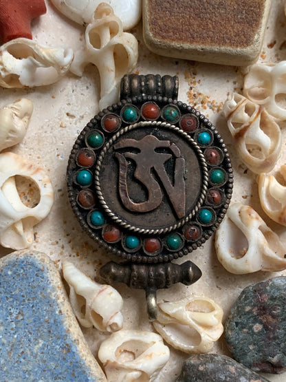 Pendentif/ Reliquaire artisanal du Népal avec pierres de turquoise et de corail sertis sur métal avec jolie gravure du Om ! De 52 millimètres de hauteur x 35 mm de largeur x 11 d'épaisseur. Vendu avec cordon noir réglable offert, parfait !