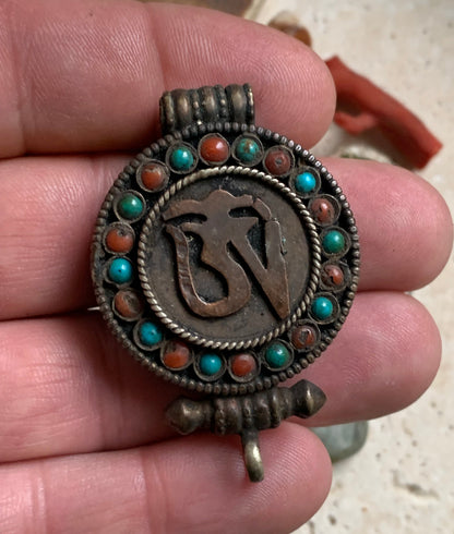 Pendentif/ Reliquaire artisanal du Népal avec pierres de turquoise et de corail sertis sur métal avec jolie gravure du Om ! De 52 millimètres de hauteur x 35 mm de largeur x 11 d'épaisseur. Vendu avec cordon noir réglable offert, parfait !