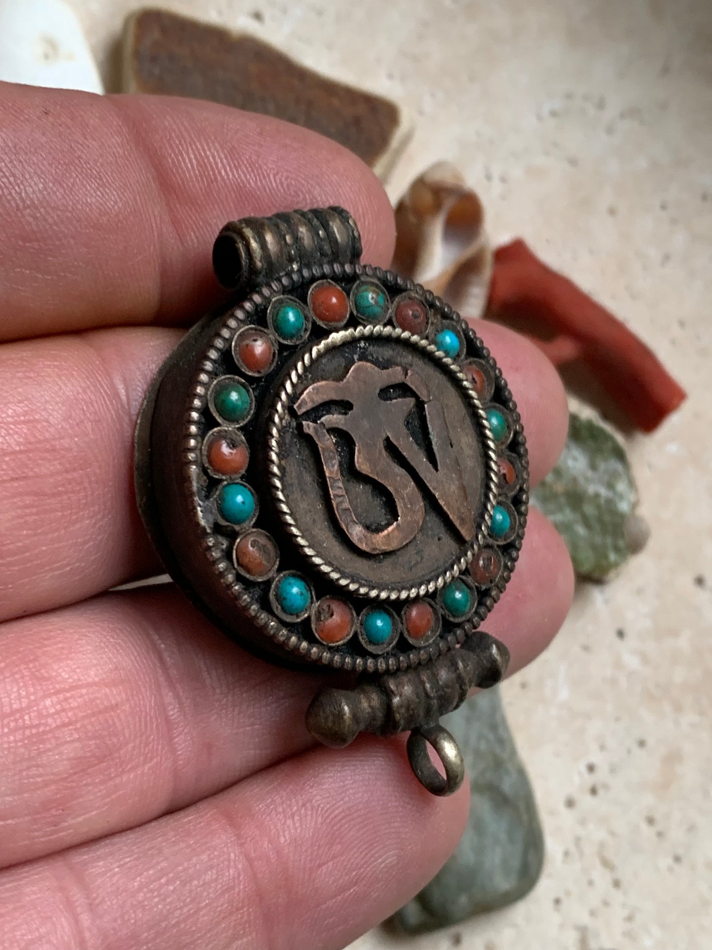 Pendentif/ Reliquaire artisanal du Népal avec pierres de turquoise et de corail sertis sur métal avec jolie gravure du Om ! De 52 millimètres de hauteur x 35 mm de largeur x 11 d'épaisseur. Vendu avec cordon noir réglable offert, parfait !