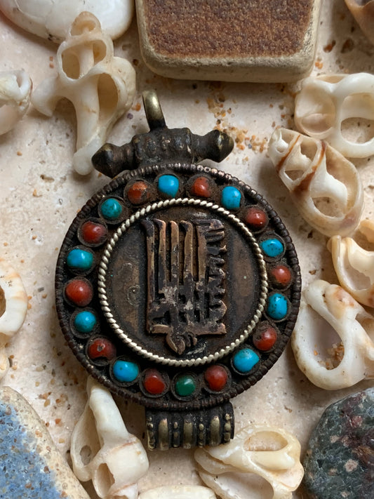 Pendentif/ Reliquaire artisanal du Népal avec pierres de turquoise et de corail sertis sur métal avec jolie gravure du Om ! De 52 millimètres de hauteur x 35 mm de largeur x 11 d'épaisseur. Vendu avec cordon noir réglable offert, parfait !