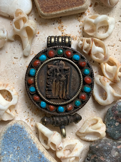 Handcrafted pendant/reliquary from Nepal with turquoise and coral stones set on metal with a beautiful Om engraving! 52 millimeters high x 35 mm wide x 11 mm thick. Sold with a free adjustable black cord, perfect!