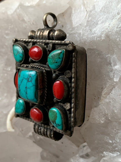 Pendentif/ Reliquaire artisanal du Népal avec pierres de turquoise et de corail sertis sur méta ! De 50 millimètres de hauteur x 35 mm de largeur x 17 d'épaisseur. Vendu avec cordon noir réglable offert, parfait !