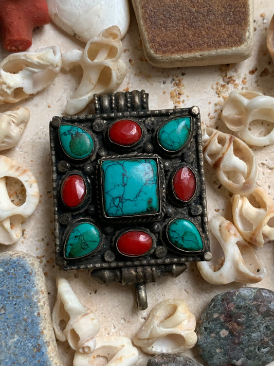 Pendentif/ Reliquaire artisanal du Népal avec pierres de turquoise et de corail sertis sur méta ! De 50 millimètres de hauteur x 35 mm de largeur x 17 d'épaisseur. Vendu avec cordon noir réglable offert, parfait !