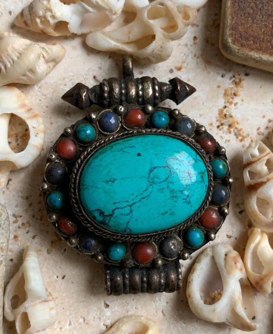 Pendentif/ Reliquaire artisanal du Népal avec pierres de turquoise et de corail sertis sur métal ! De 48 millimètres de hauteur x 37 mm de largeur x 18 d'épaisseur. Vendu avec cordon noir réglable offert, parfait !