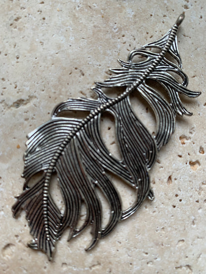 Pendentif en métal argenté en forme de plume. De 85 x 40 x 5 millimètres. Vendu avec cordon noir réglable offert, parfait !