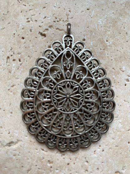 Pendentif en métal argenté en forme de Mandala. De 60 x 44 x 5 millimètres. Vendu avec cordon noir réglable offert, parfait !