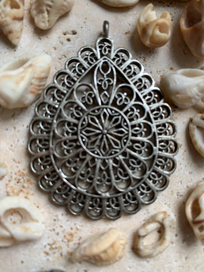 Pendentif en métal argenté en forme de Mandala. De 60 x 44 x 5 millimètres. Vendu avec cordon noir réglable offert, parfait !