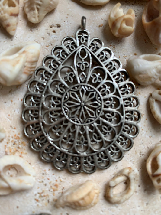 Pendentif en métal argenté en forme de Mandala. De 60 x 44 x 5 millimètres. Vendu avec cordon noir réglable offert, parfait !
