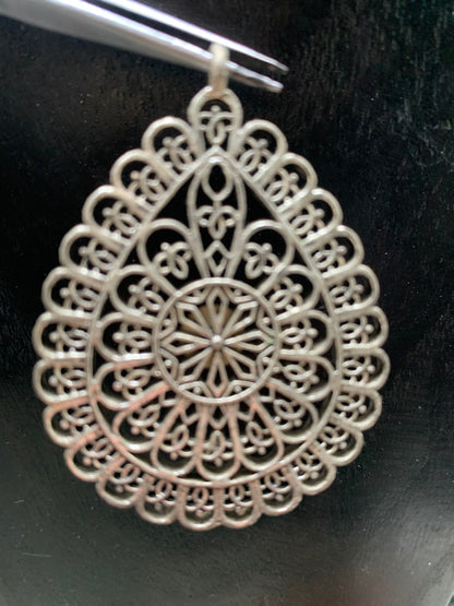 Pendentif en métal argenté en forme de Mandala. De 60 x 44 x 5 millimètres. Vendu avec cordon noir réglable offert, parfait !