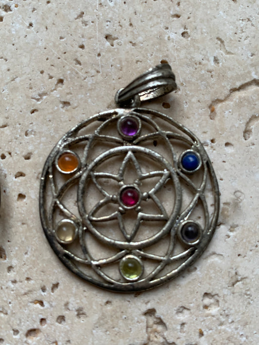 Pendentif '7 chakras' de 35 millimètres de diamètre, en métal argenté (laiton). Vendu avec cordon réglable de couleur noire !