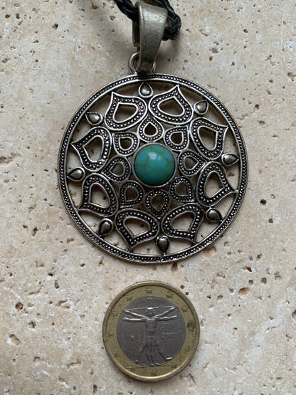 Pendentif en métal argenté en forme de Mandala avec cabochon d'howlite bleue au centre. De 48 x 12 millimètres. Vendu avec cordon noir réglable offert, parfait !