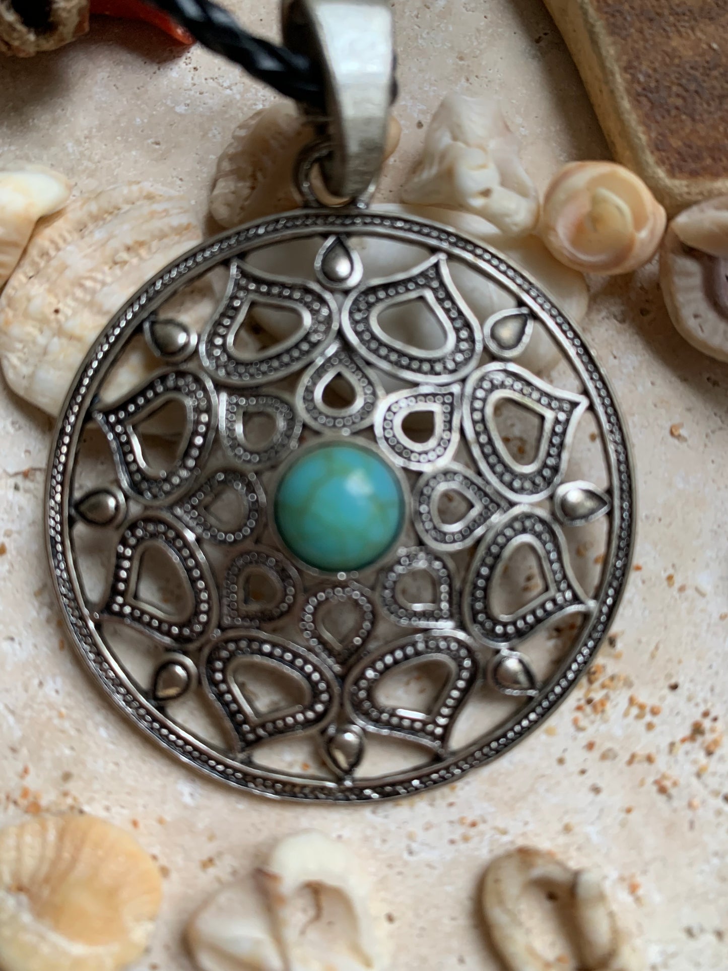 Pendentif en métal argenté en forme de Mandala avec cabochon d'howlite bleue au centre. De 48 x 12 millimètres. Vendu avec cordon noir réglable offert, parfait !