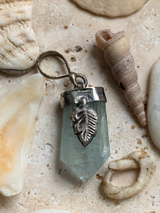 Aquamarine pendant set in silver with a metal design! Unique piece measuring 38 millimeters high x 12 millimeters wide x 8 millimeters thick. Sold with an adjustable black cord. Made in Pakistan!