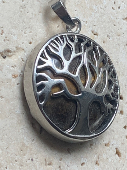 Pendentif en métal argenté 'Arbre de vie' avec un oeil de tigre en fond, de 27 mm de diamètre. Vendu avec cordon noir réglable, parfait !