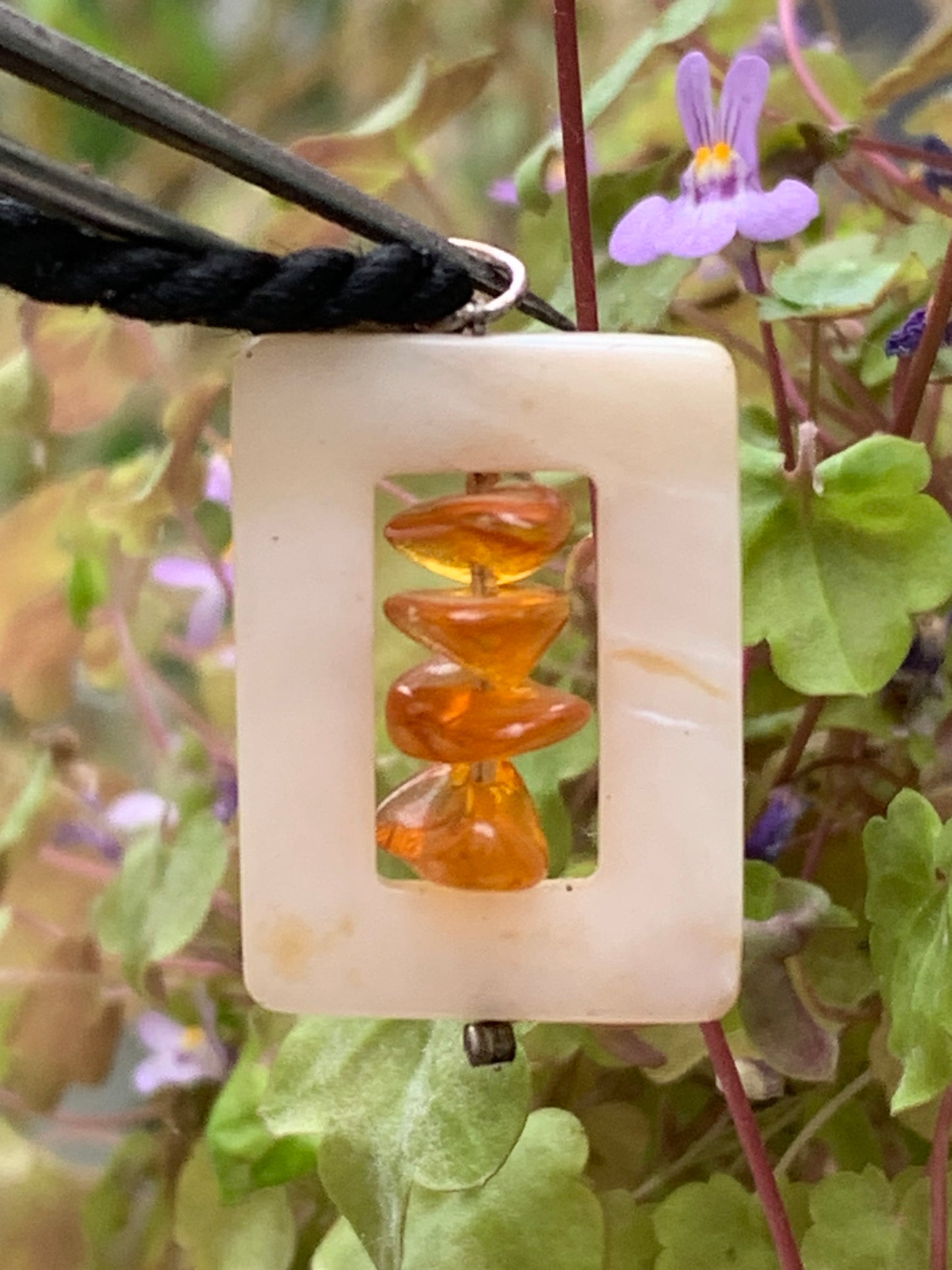 Amber and mother-of-pearl, pendant measuring 31x17x9 millimeters, sold with a sliding (adjustable) black leather cord measuring 40 to 70 centimeters!