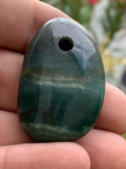 Jade, galet percé 43 mm de hauteur x 30 de largeur x 12 d'épaisseur. Vendu avec cordon réglable de couleur noire.