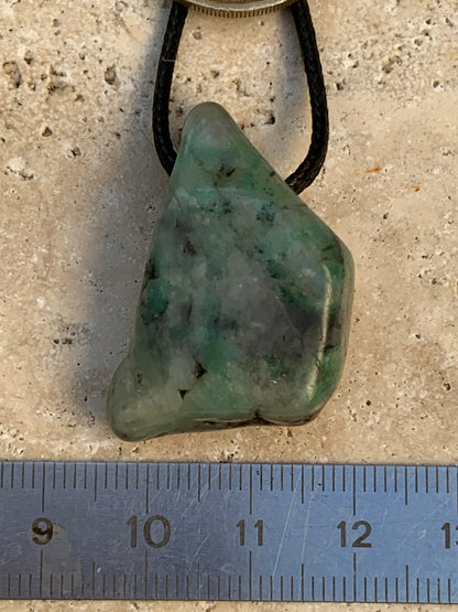 Émeraude, pierre brute percée de 33mm x21 x12 - 12,4 grammes. Vendu avec cordon noir réglable !