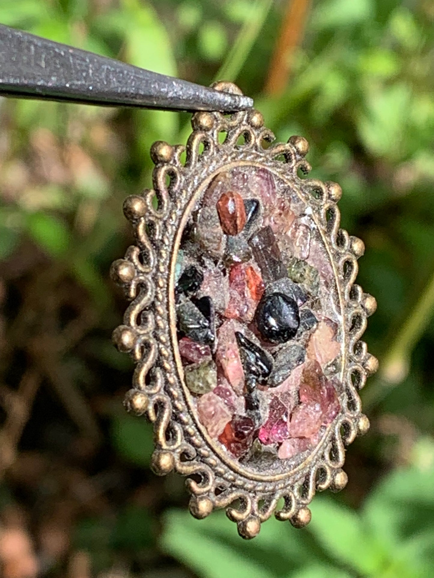 Médaillon couleur Bronze avec Tourmaline multicolore, de 36 mm de ht x30 x 8. Vendu avec un cordon noir réglable !