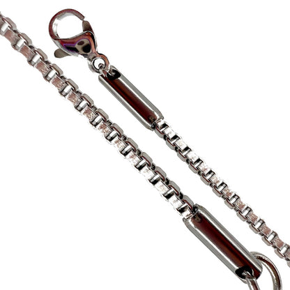 Chaîne à maille carrée est terminée par des embouts en acier intégrés au fermoir et à l’anneau, ce qui renforce la solidité de l'ensemble.  Longueur : 50 cm